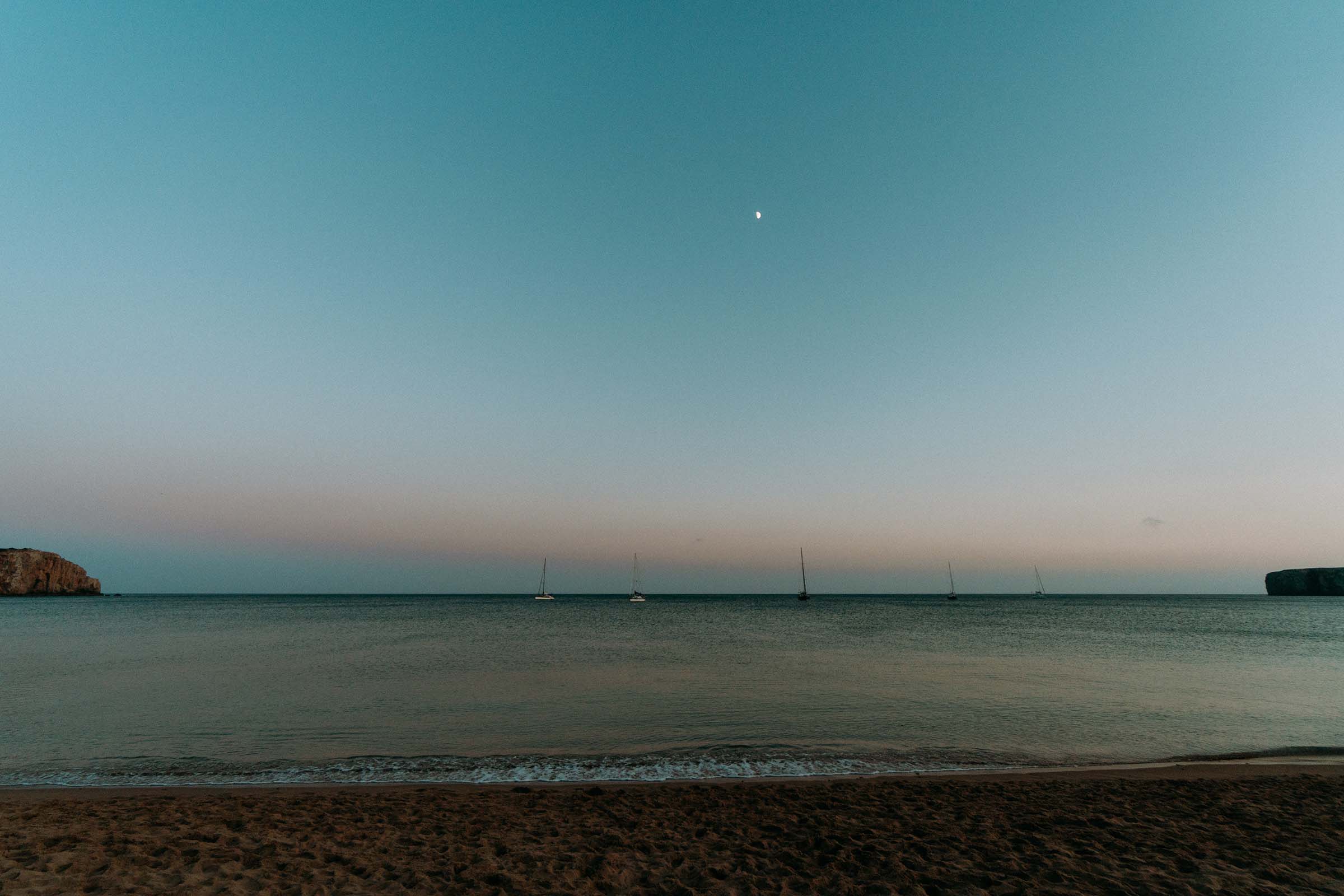 dusk at the beach with boats far away