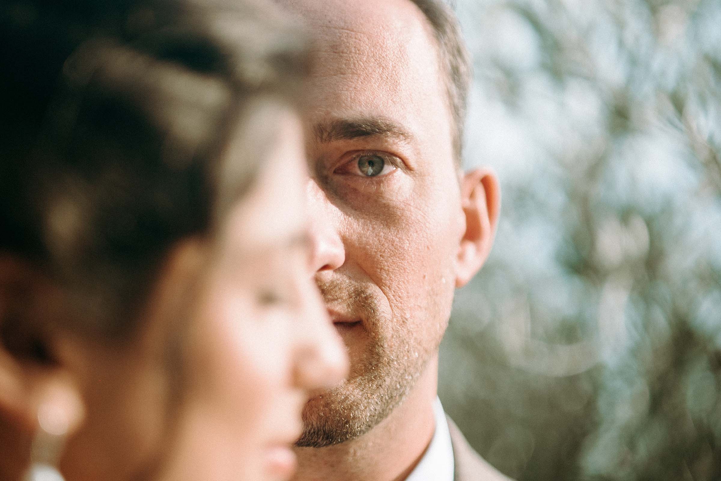 groom with green eyes staring straight into the camera with bride covering half of the face