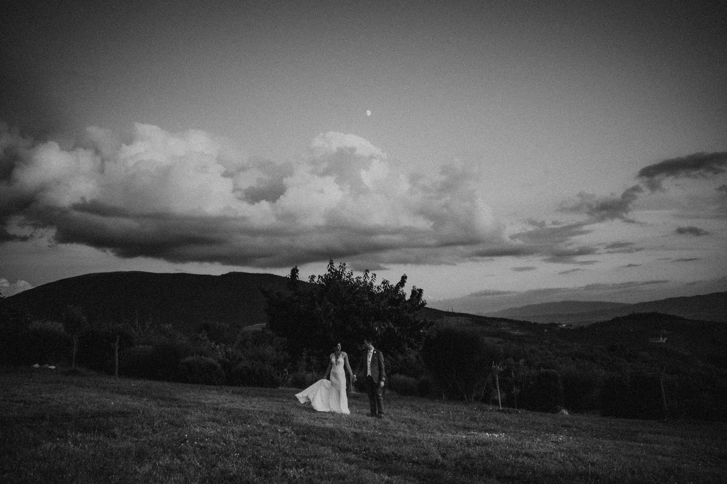 black and white photo if a couple and the moon above