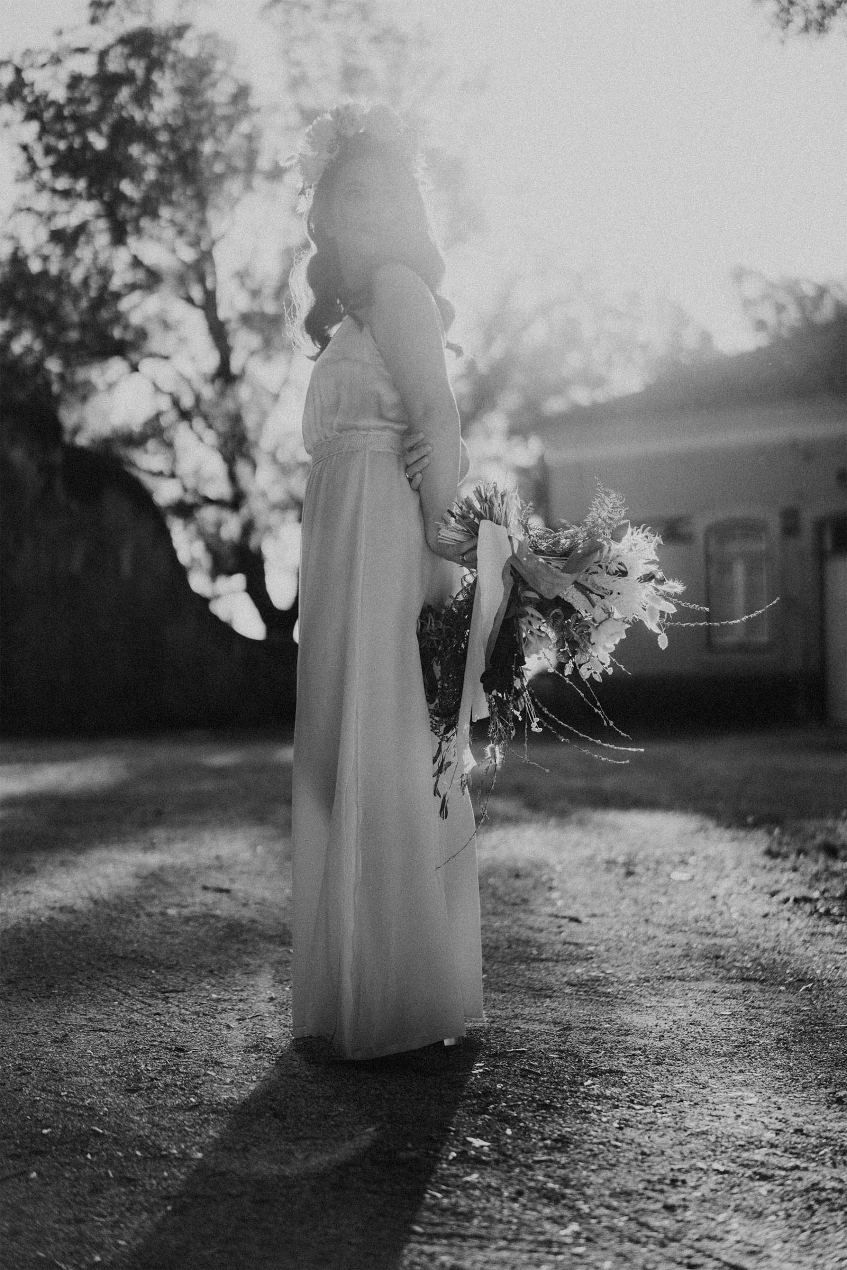 black and white photo of a bride holding her bouquet behind her back