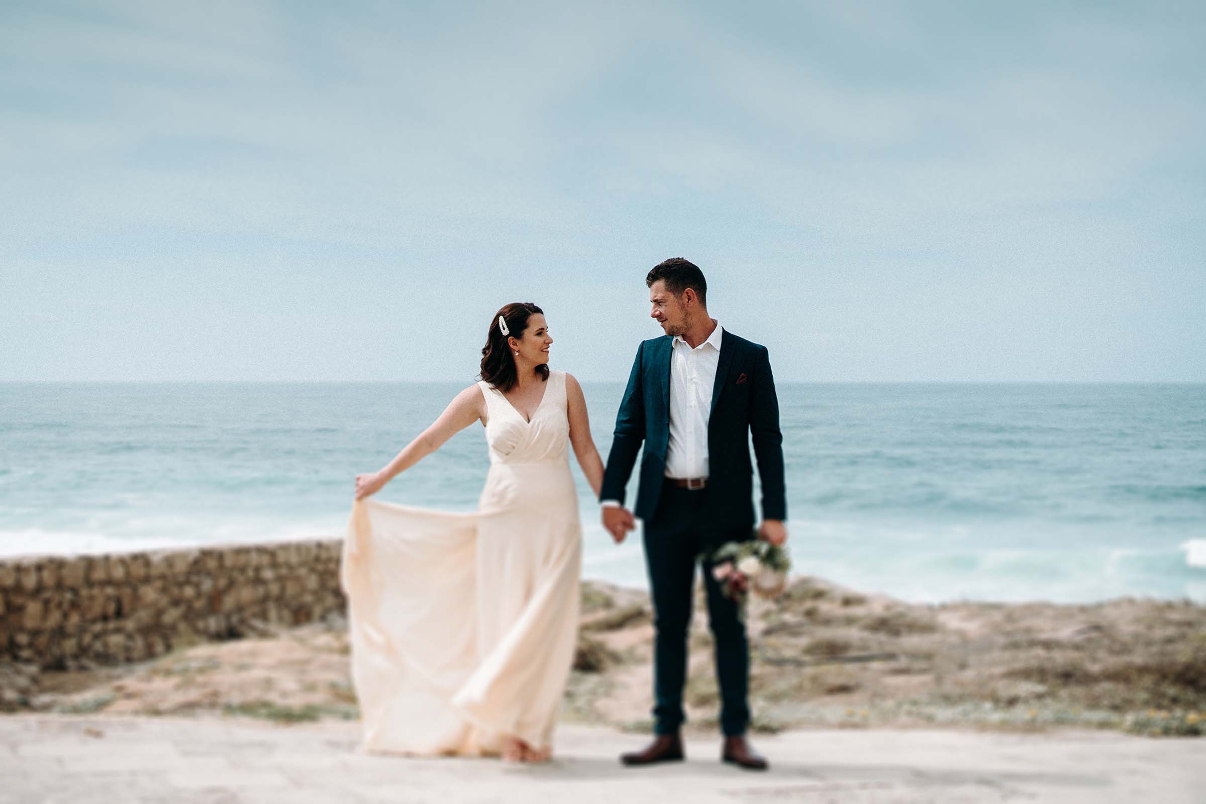 freelens photo of couple while bride holds her dress to the side