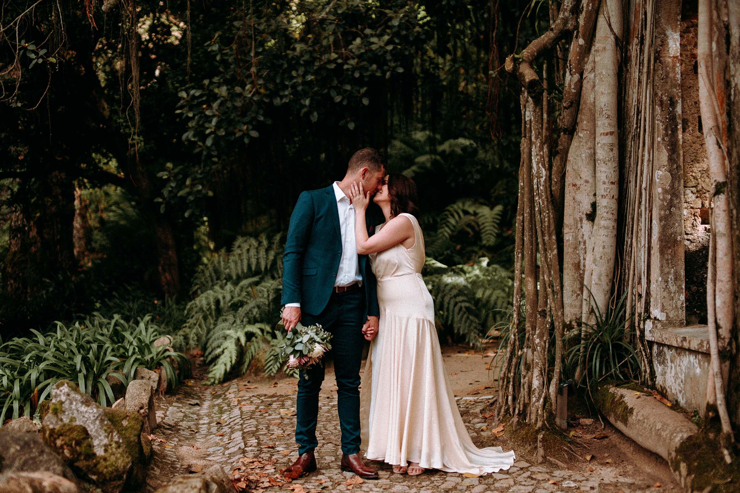 couple kissing in monserrate garden while groom hold bouquet