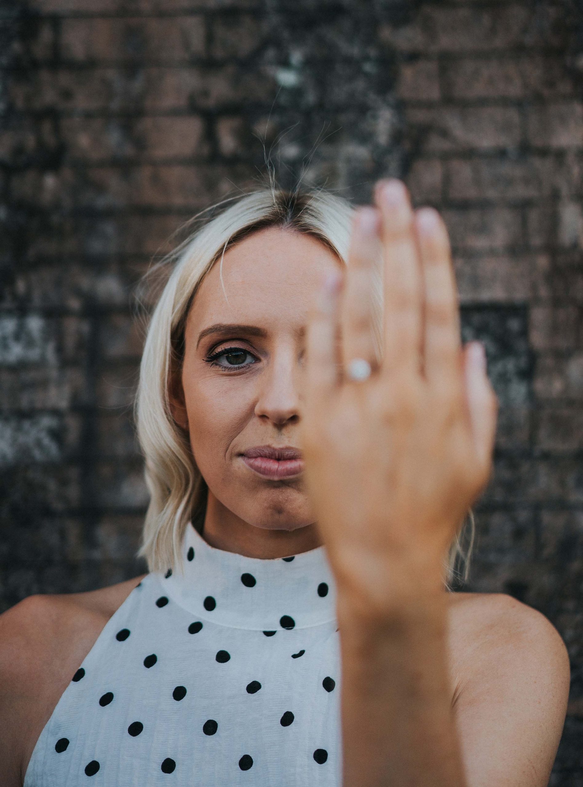 bride covering half of face with hand with engagement ring out of focus