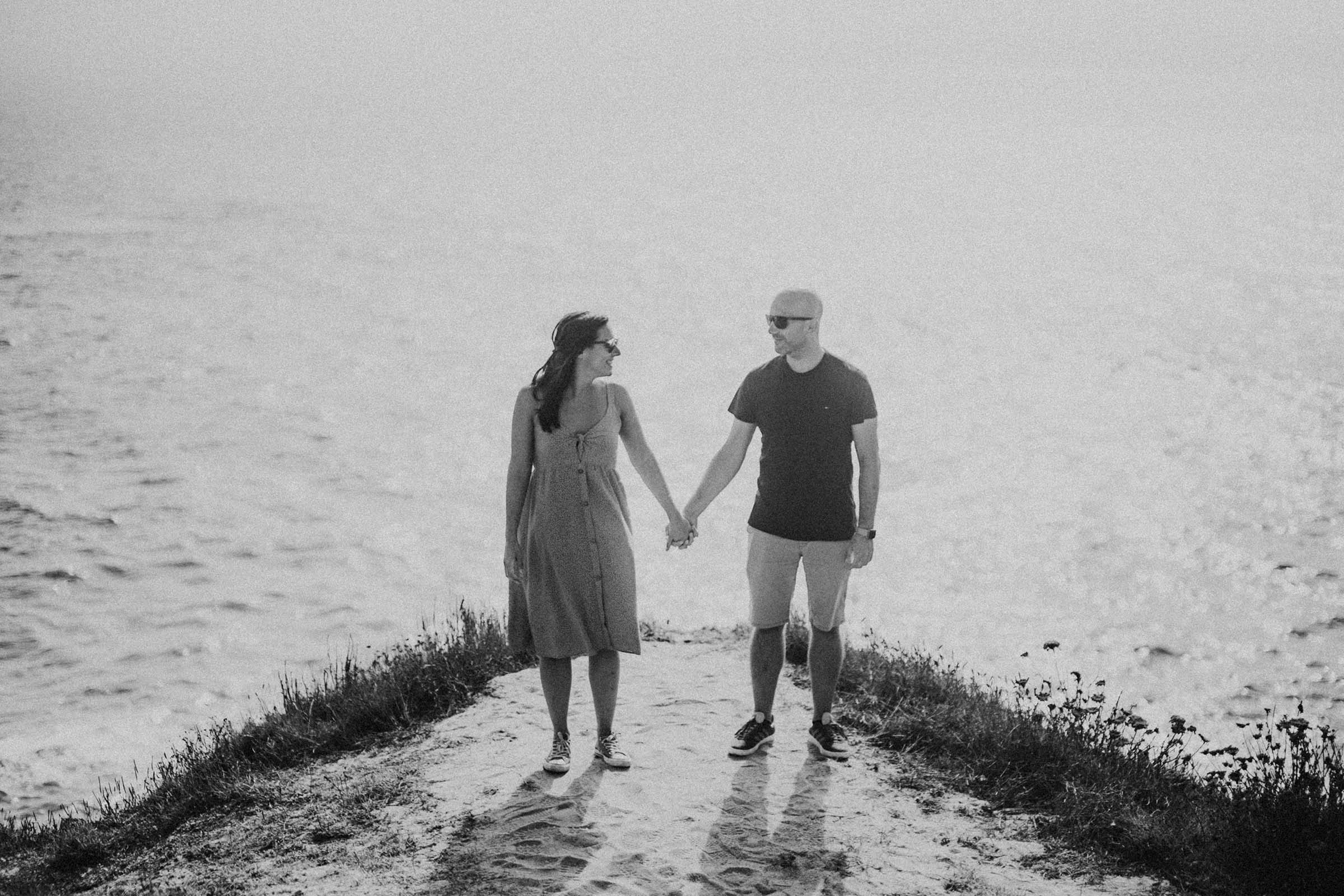 black and white photo holding hands on a cliff