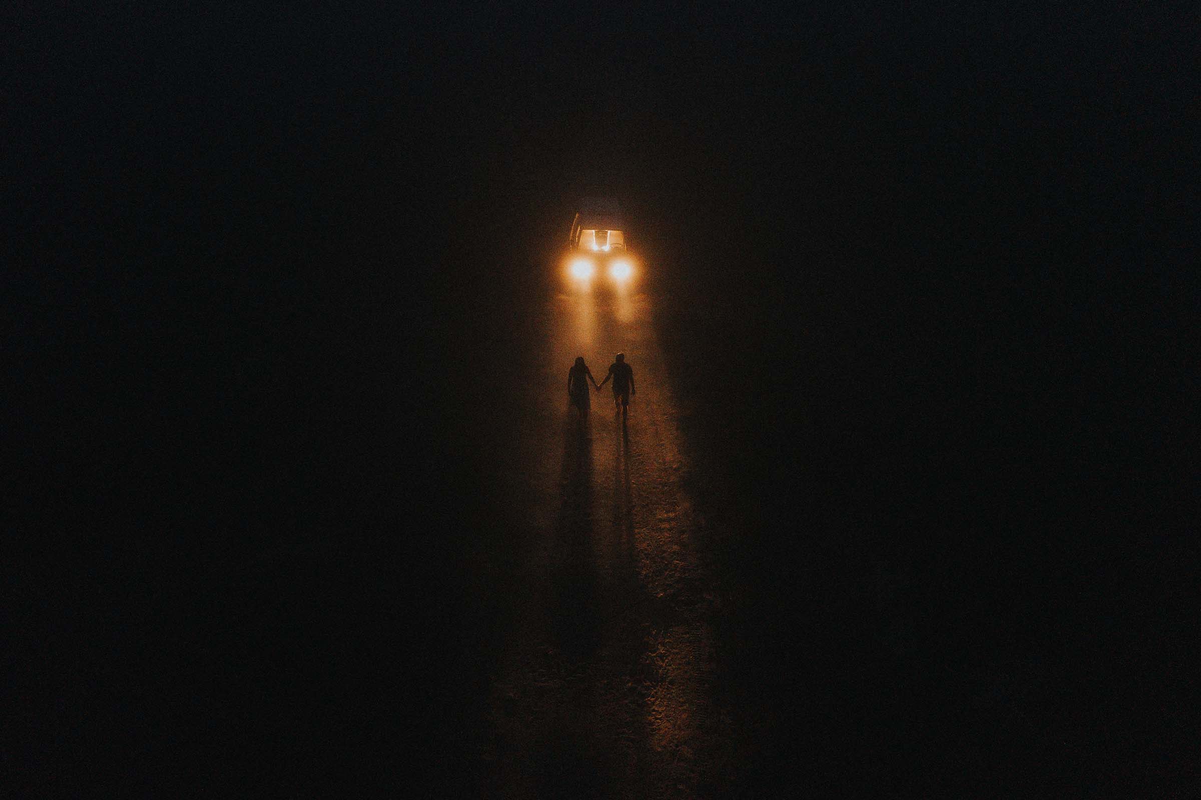 night photo couple walking away from the van headlights on