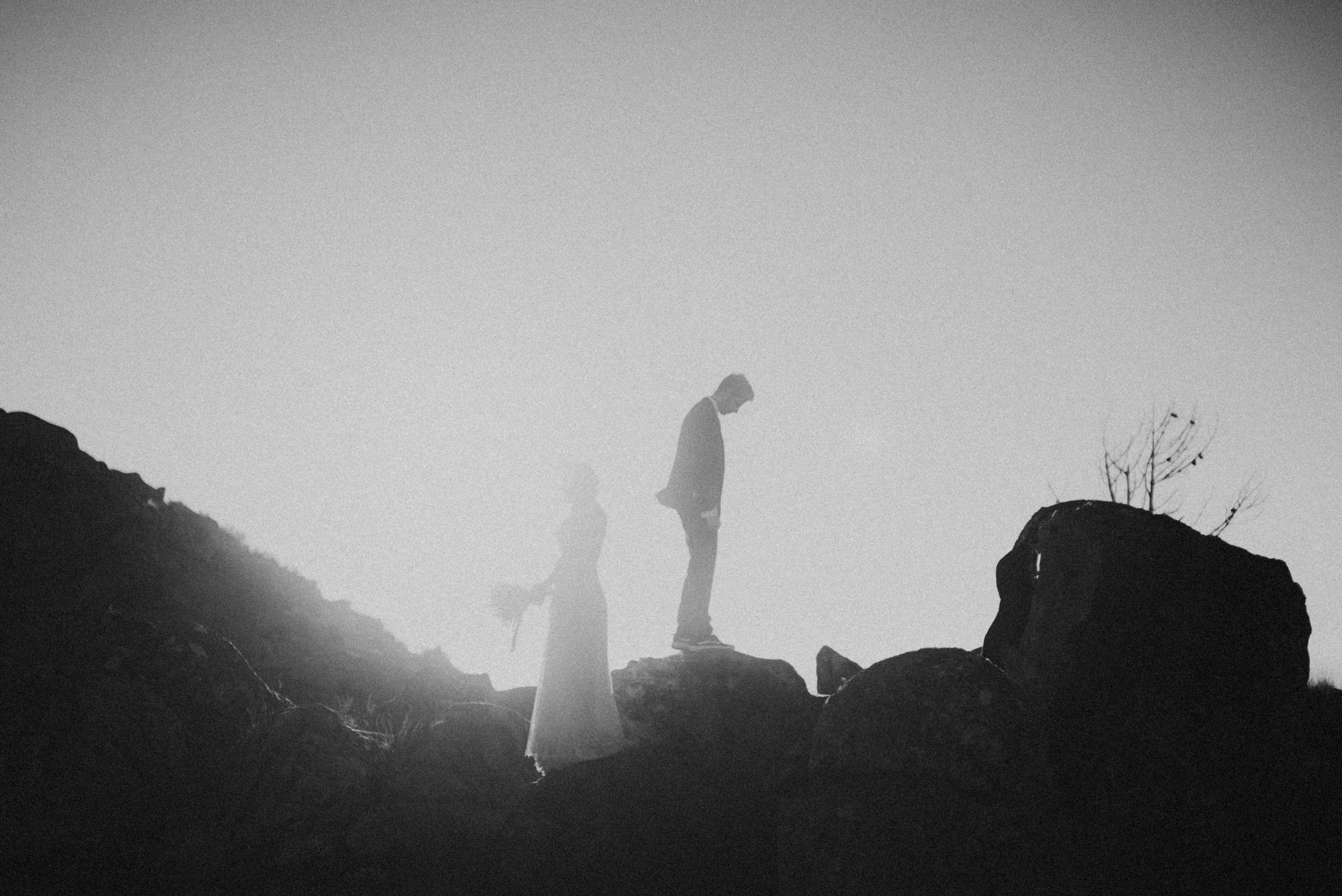 couple on top of a mountain with sun behind in black and white